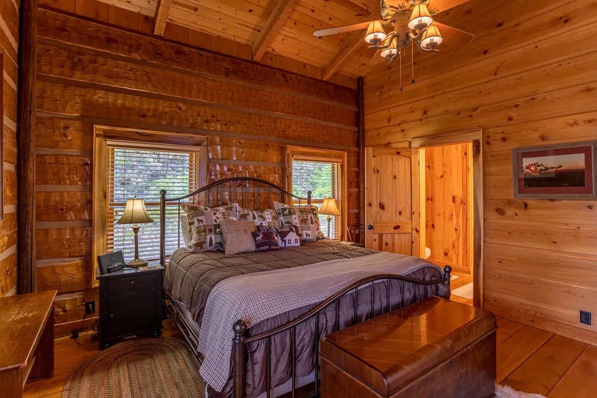 A tranquil bedroom with a comfortable bed, nightstands with lamps, and windows that allow natural light to fill the space. The room features soft, neutral tones and a classic chest at the foot of the bed, creating an inviting and peaceful retreat.